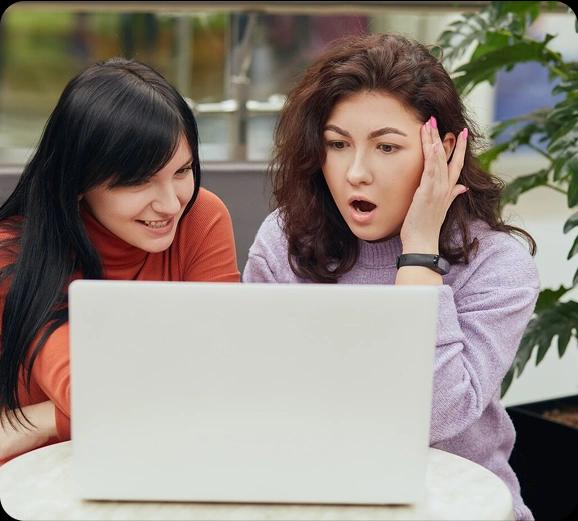 Two friends surprised while looking at a laptop
